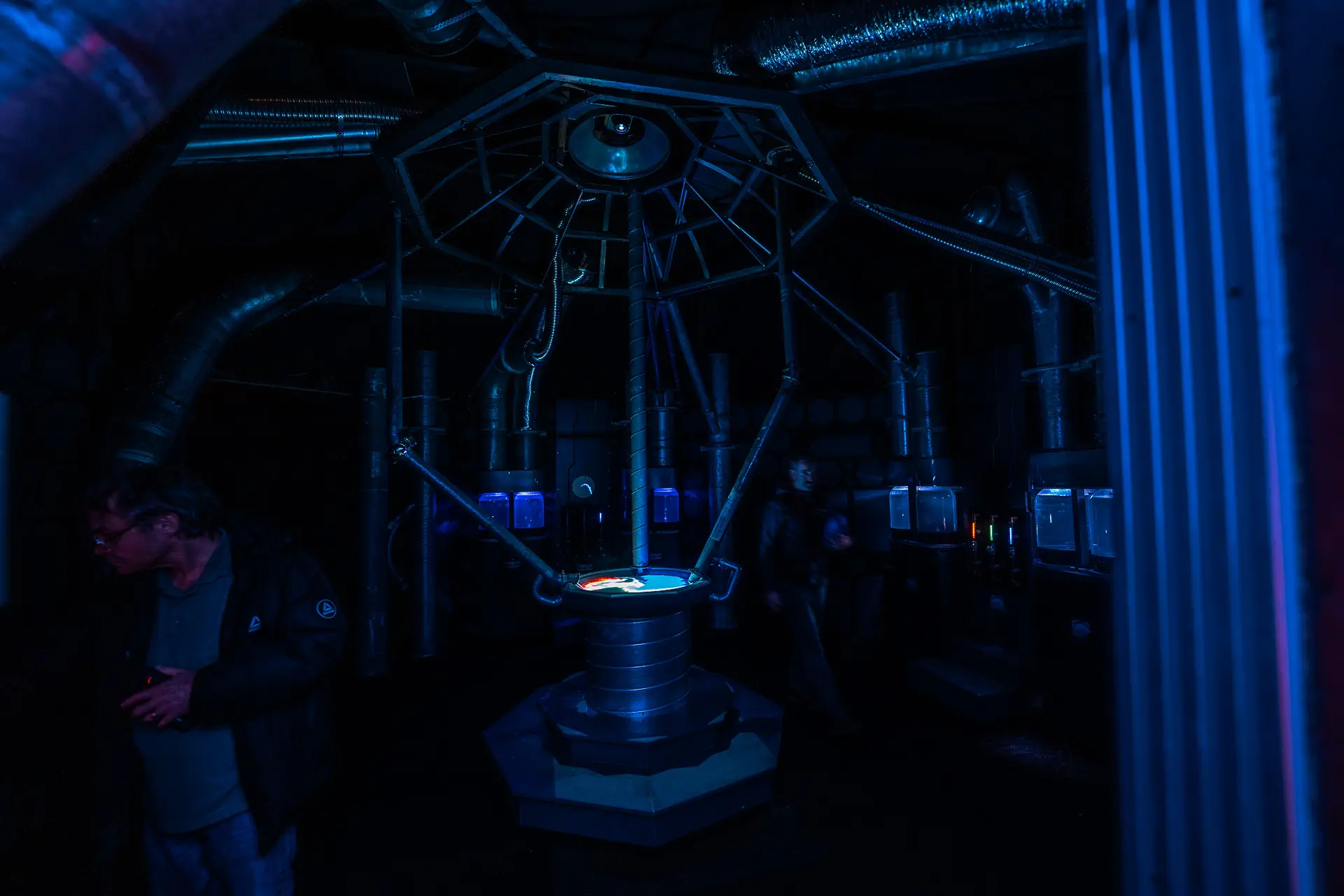 Audience members observing the live projected fluid simulation as colours swirl through the chamber