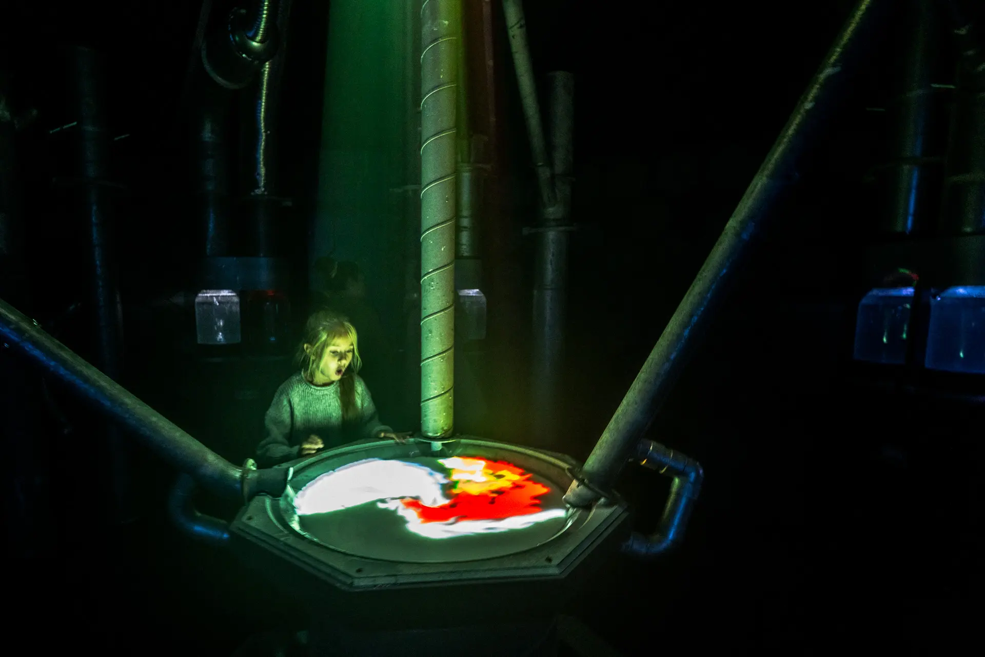 Wide view of Concoct's laboratory set with visitors operating controls around the central mixing chamber